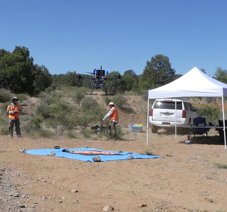 Crew operating drone by tent work station and testing equipment