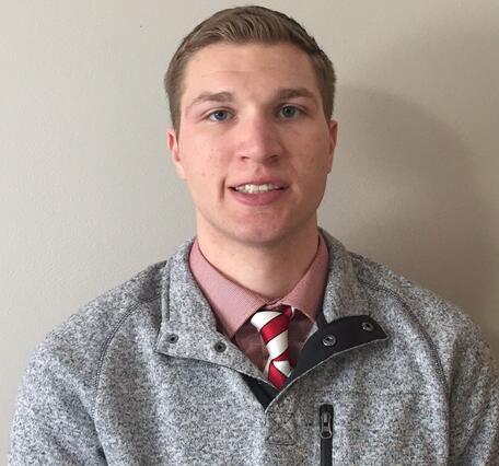 Smiling man standing in front of tan wall