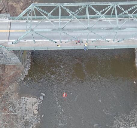 An aerial view of hydrologic technicians on a truss bridge above Brandywine Creek measuring streamflow with an ADCP.