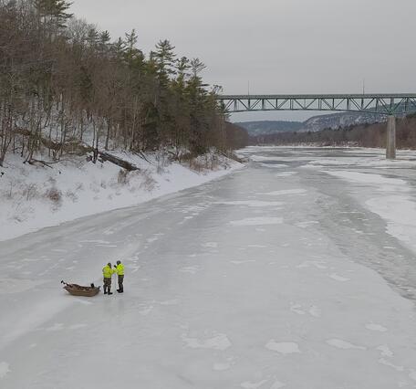 Two men standing next to an Ice Sled on the frozen Delaware River as they prepare to make a measurement