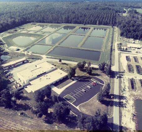 The National Fishery Research Laboratory in Gainesville, Florida is shown in an aerial photo from 1989. The building and research ponds are visible along with the surrounding forested landscape