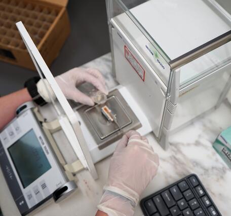 Scientist weighing sample on analytical lab balance