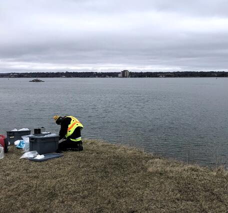 Scientist sampling water near shoreline of river on an overcast day