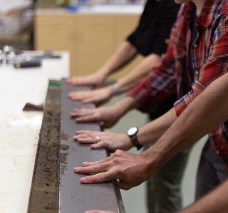 Scientists separating a sediment core split lengthwise