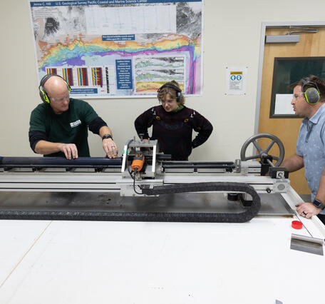 Scientists splitting a sediment core with the GeoTek core splitter