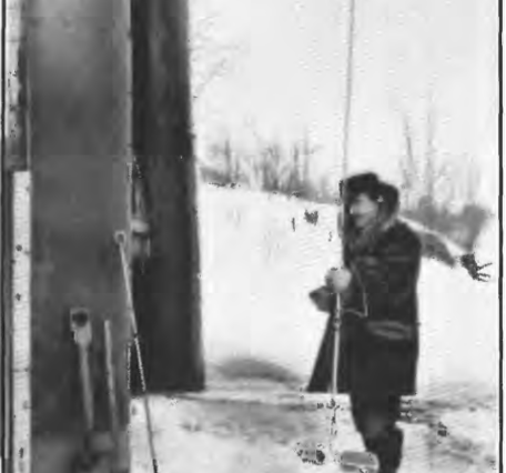 Black and white historic picture of a scientist holding a measuring rod in a hole chiseled in the ice below him