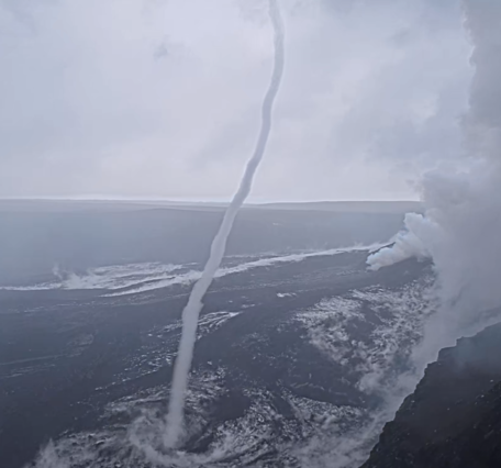 Color photograph of a whirlwind near a steamy volcanic vent in a crater