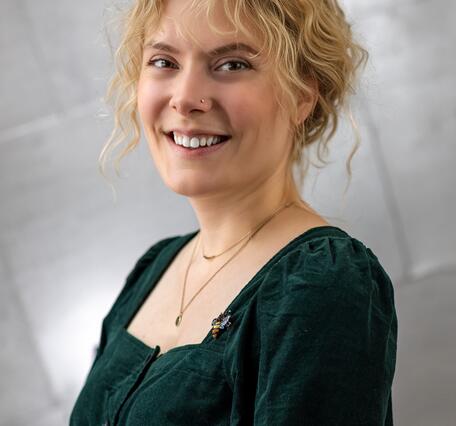 A woman with blonde hair and a green blouse smiles for her picture. 