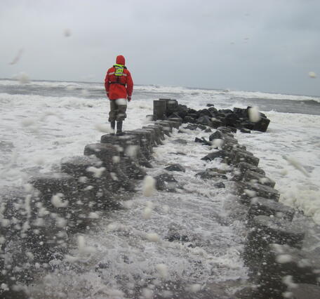 USGS scientist measuring high water marks on a jetty into the Long Island Sound during flooding.