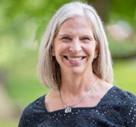 Profile photo for Stacy Curtis, a blonde woman in front of a green forested background.