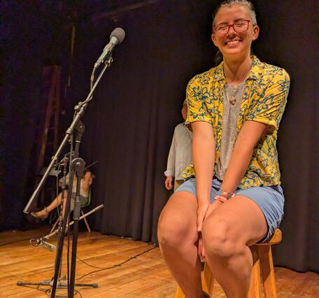 person sitting on stool next to microphone smiling