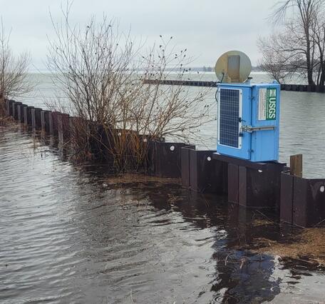 Blue USGS streamgage housing sits at outlet to lake