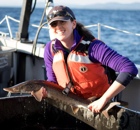 Graduate student is holding a sturgeon