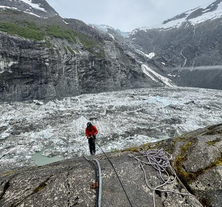Person in a red jacket standing near a basin covered in ice.