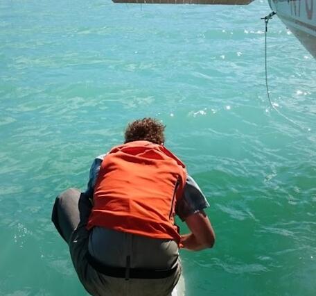 A scientist collects a water sample from a glacial lake next to a seaplane in Alaska