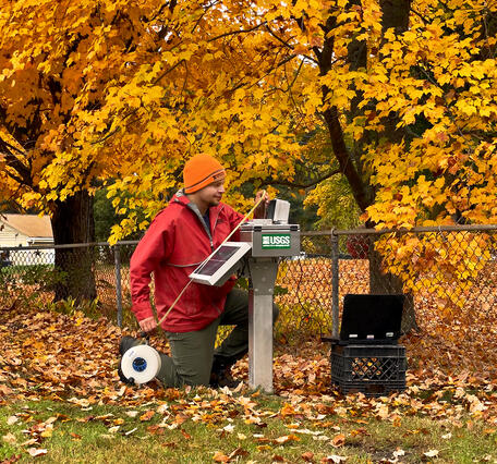 USGS scientist reads an electronic tape measure that has been lowered into a groundwater well during fall.