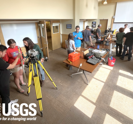 groups of students in a well-lit room huddle around various stations of equipment demonstrations