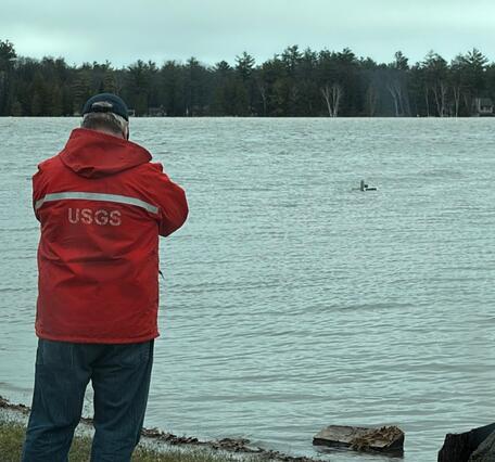 Hydrologic technician views submerged streamgage house in flooded lake