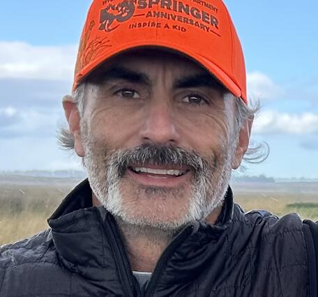 man in an orange hat smiling into camera