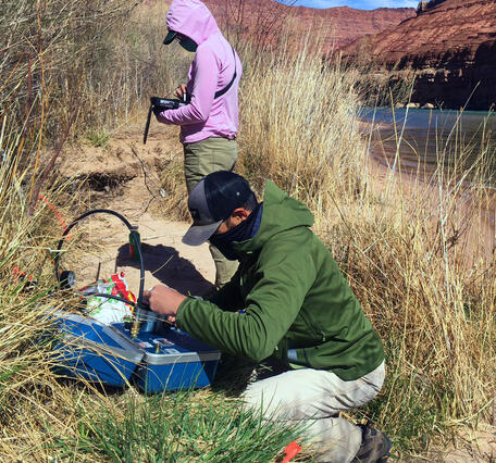 A man and woman collect vegetation data on the bank of the Colorado River in Grand Canyon