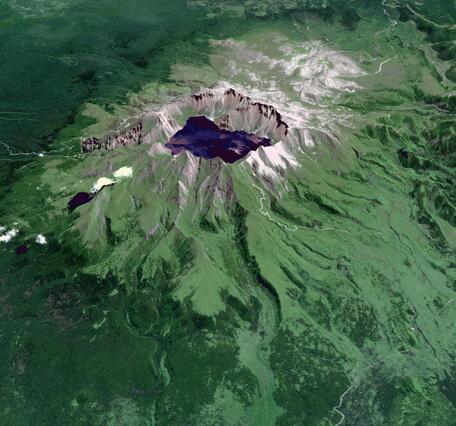 Satellite image of a volcano crater filled with a lake and green vegetation down much of the sides