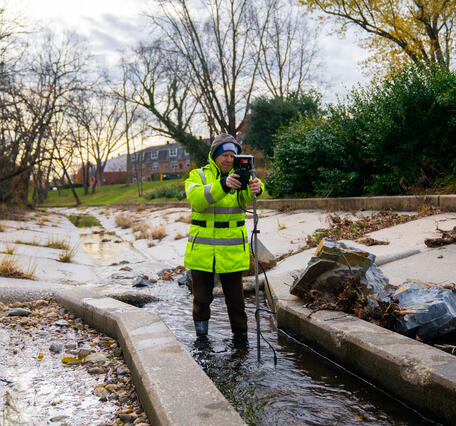 Hydrologic technician Mike Geissel standing in a stream with a device to measure streamflow.