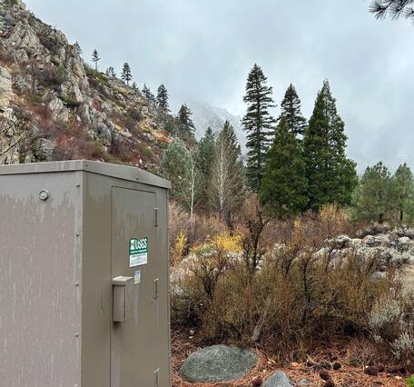 Cloudy sky over West Fork Carson River with rock outcrops, sagebrush, and pine trees.