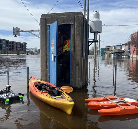 Hydrologic technician inside gage house with kayak and two ADCPs floating outside