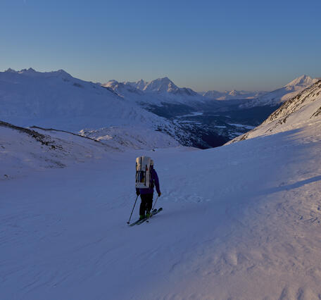 Person with a backpack skiing down a glacier.