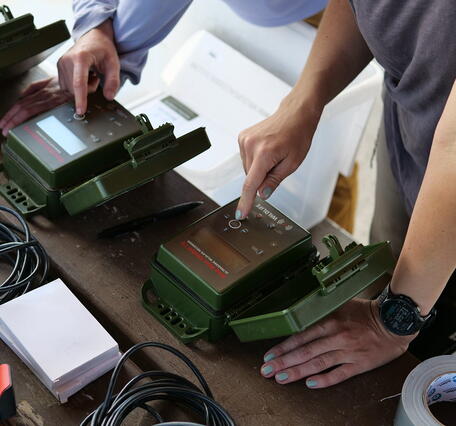 hands touch different acoustic devices on a table