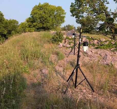 Air sampling units rest on top of a grassy and rocky hill