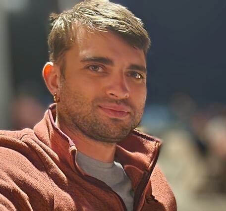 Image of a smiling man in an orange shirt with brown hair