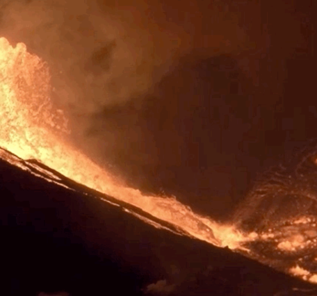 Animation showing bright orange lava erupting at night and flowing into a pool of lava.