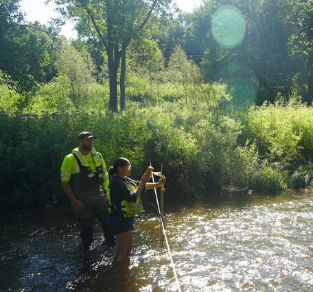 Two people standing in a stream take a discharge measurement