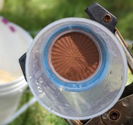 An opened eDNA filter cartridge showing the membrane with eDNA sample and red sediment