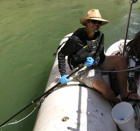 On a research boat in the Grand Canyon, a man collects samples from the Colorado River using an eDNA sampler.