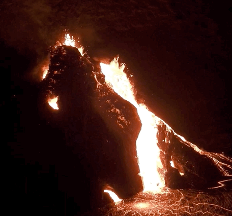 Lava bubbling out of a fissure at night time.