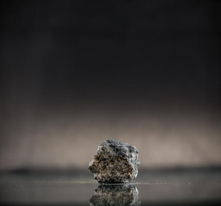  Isolated lump captured in high-definition photography, emphasizing flaky texture and dark gray color.