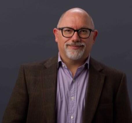 man wearing glasses, purple shirt, and brown blazer