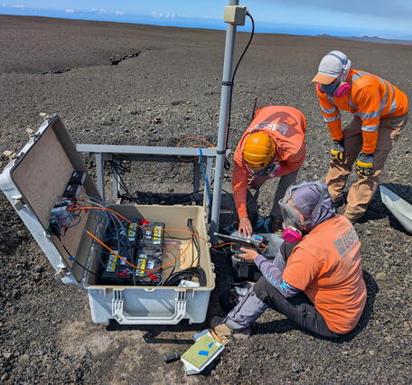 Scientists work gather around a volcano monitoring station 