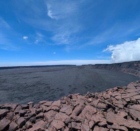 Color photograph of caldera with blue sky in the background
