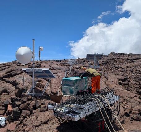 Color photograph of person working on monitoring equipment in the field