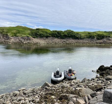 Two boats anchored to a rocky shoreline.