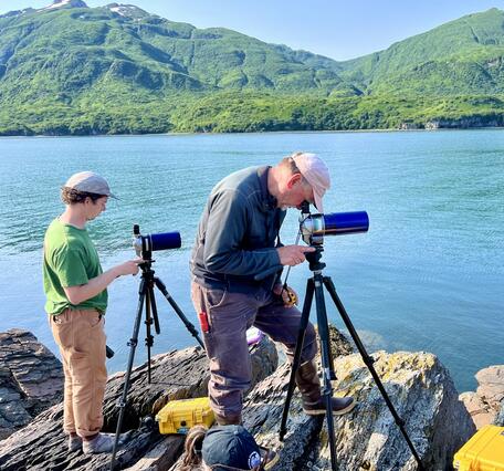 Two people looking through telescopes.