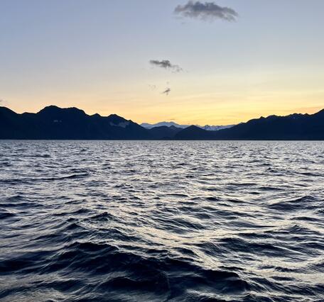 Yellow sunset over mountains and water.