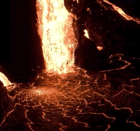 Lava flowing as a waterfall at night into a lava lake