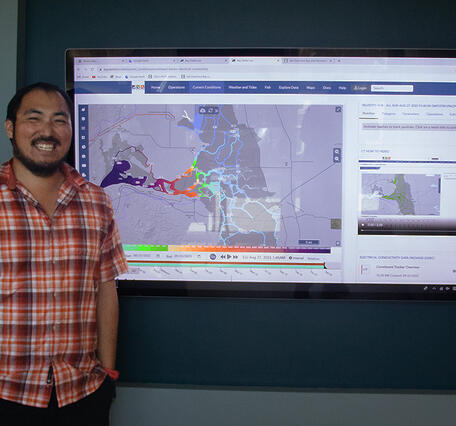Lawrence Fujiwara stands next to display showing Bay-Delta real time electrical conductivity conditions.