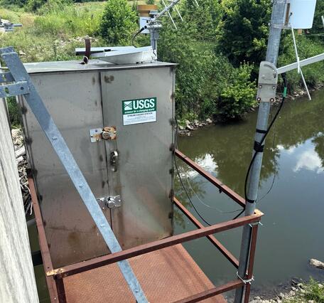 Streamgage housing on bridge on a summer day