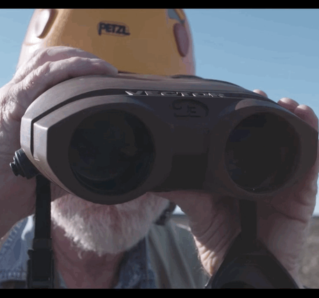 Animated GIF of a scientist looking back and forth with a range finder.