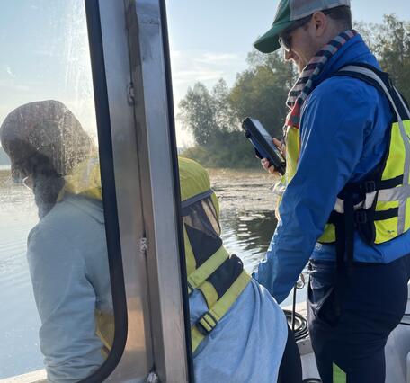 Two scientists measure water quality from a boat